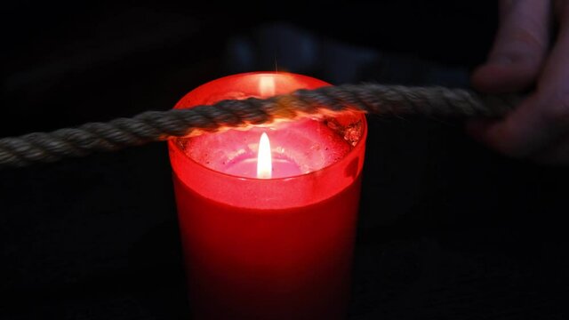 Burning a jute rope on the fire of a candle for the shibari ritual. 
