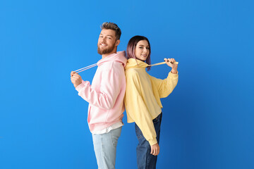 Cool young couple in hoodies on color background