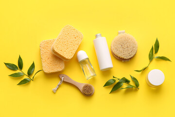 Obraz na płótnie Canvas Set of bath supplies with sponges and plant branches on yellow background