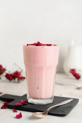 Glass of tasty rose latte on light background