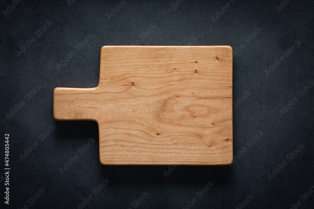 Poster handmade cherry wood cutting board on the dark tabletop. - Posters
