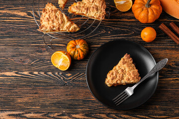 Plate and grid with pieces of tasty pumpkin pie on wooden background