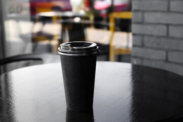 Takeaway cup of tasty latte on table in outdoor cafe