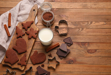 Board with tasty chocolate Christmas cookies and glass of milk on wooden background