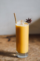 yellow beverage in tall glass with ice turmeric thai iced tea with star anise