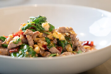 Close up to the warm Stir-Fried Beef Basil, ready to serve and eat. A Famous Thai Food Style in white bowl is set in studio light.