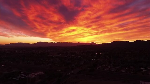 Aerial view of a Fire Sunset over the Estrella Mountains and South Mountain near Tempe Arizona, Red yellow orange clouds