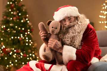 Santa Claus with teddy bear in room on Christmas eve