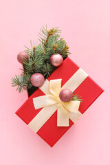 Composition with Christmas gift box, balls and fir branches on pink background