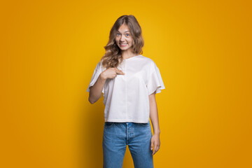 Fototapeta premium Exicited caucasian woman pointing with index finger on her while standing isolated over yellow background.
