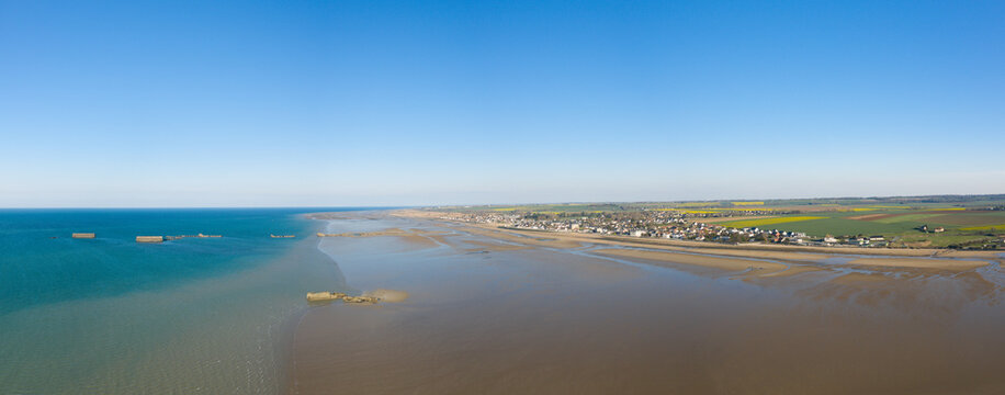 The panoramic view of the artificial port of Gold beach on the sandy beach of Asnelles in Europe, France, Normandy, Arromanches les Bains, in summer, on a sunny day.