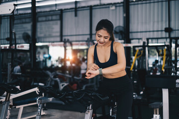 Fototapeta na wymiar Happy young woman smiling and working out with sport biking fitness at class against fitness interface.