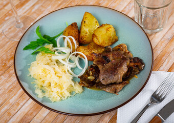 Rabbit liver dish with boiled potatoes and sauerkraut