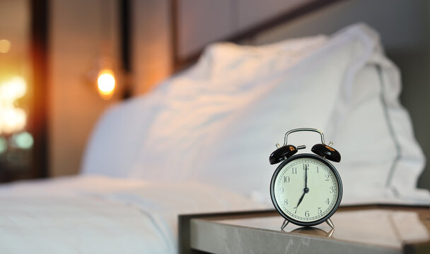 7 O’clock alarm clock picture in bedroom with bed blurred image background