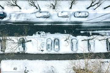 parked cars covered with snow during heavy snowfall in winter cold day. drone photo from above.