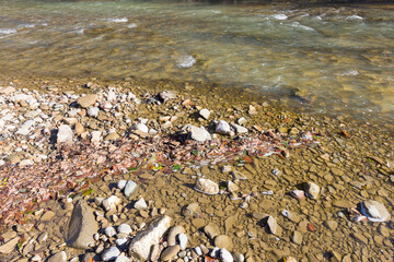 Autumn, the shallow stone-sandy bottom of a mountain river in the rays of the morning sun, close-up.