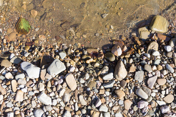 Autumn, the shallow stone-sandy bottom of a mountain river in the rays of the morning sun, close-up.