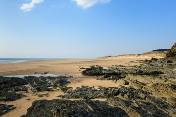 The beach of the Old Church and its black eroded rocks in Europe, France, Normandy, Manche, in spring, on a sunny day.