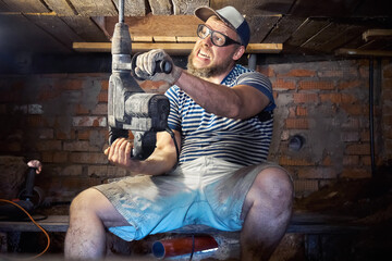 Fototapeta premium Funny bearded man with heavy duty perforator in the basement of the house