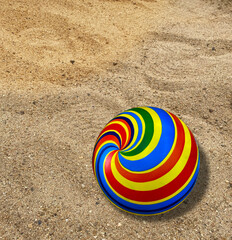 THE BRIGHT RAINBOW COLOPRED BEACH BALL IN THE SAND AT SUMMER DAY ,