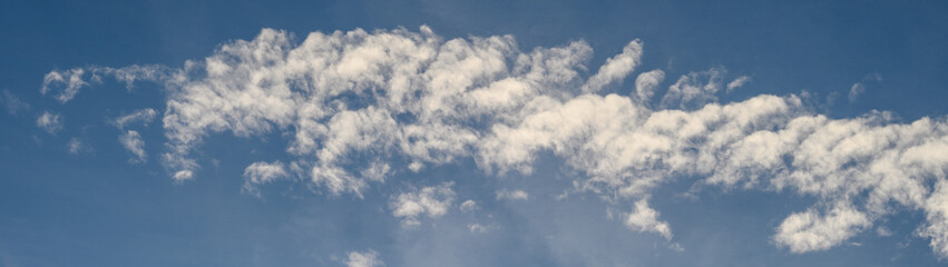 Dramatic cloudscape with fast moving white clouds against a blue sky, as a nature background
