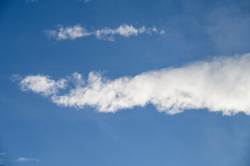 Naklejka premium Dramatic cloudscape with fast moving white clouds against a blue sky, as a nature background 