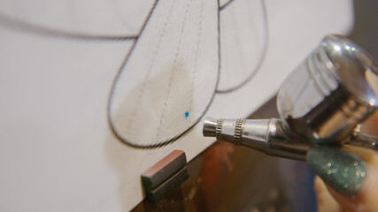 Woman artist learns to paint with airbrush with acrylic dye, paper and easel. Concept modern art, airbrushing, aerography, graffiti, aerosol spray