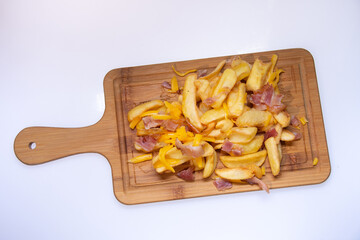 french fries with ham on a wooden plate