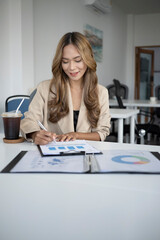Obraz na płótnie Canvas Portrait of beautiful businesswoman analyzing financial graphs charts in office.