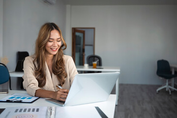 Cheerful businesswoman working with computer laptop in office.