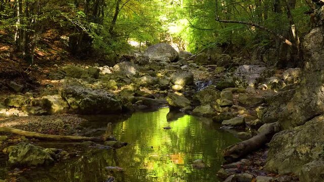 View of a beautiful waterfall and the cloud of tiny water drops under the sun rays and lens flares. Camera panningement. Gimbal shot