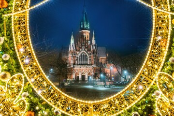 Świąteczne, bożonarodzeniowe ozdoby przed kościołem w Krakowie podświetlone