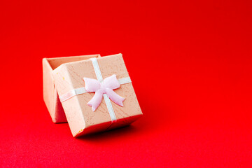 pink gift box with an open lid on a red background with copyspace