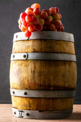 wooden wine barrel and grape brush on black background