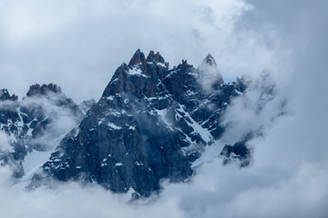The Aiguille de Blaitiere surrounded by clouds in the Mont Blanc massif in Europe, France, the Alps, towards Chamonix, in summer, on a cloudy day.