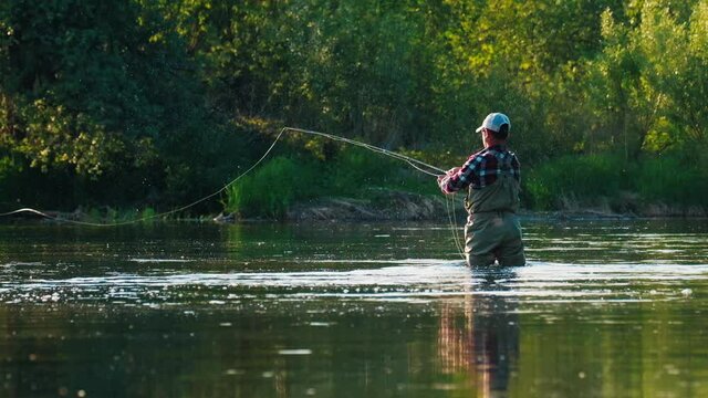 Fly fishing. Man fly fishing on the wild river with lots of insects flying in the air