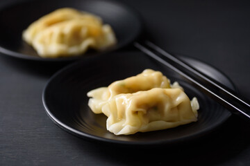 Wonton stuffed, gyoza or dumplings, Asian cultural food on black background