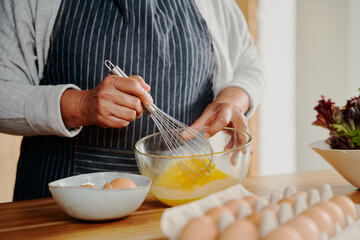 Close up of hands, elderly multi-cultural female whisking eggs for breakfast. Retired, healthily at home.