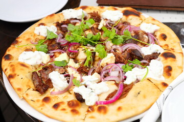 A colorful pizza on a plate at a restaurant.