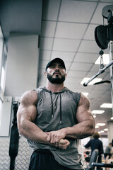 Fototapeta na wymiar strong young caucasian male with beard showing strong muscles indoors gym