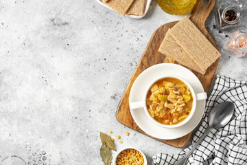 Pea soup with chicken in a white plate on a light cooking table