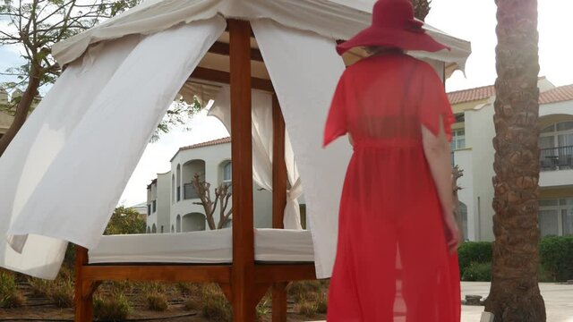 Summer vacation woman in red hat and cape for the beach with mobile phone near swimmimg pool amd palms, woman blogger