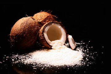 Wiórki kokosowe i kokos. Skorupa orzecha kokosowego z płatkami kokosowymi i czarnym tłem. Kokosy na każdą okazję i produkt, kosmetyki, żywność, beauty, potencje. Miłość i czułość - obrazy, fototapety, plakaty