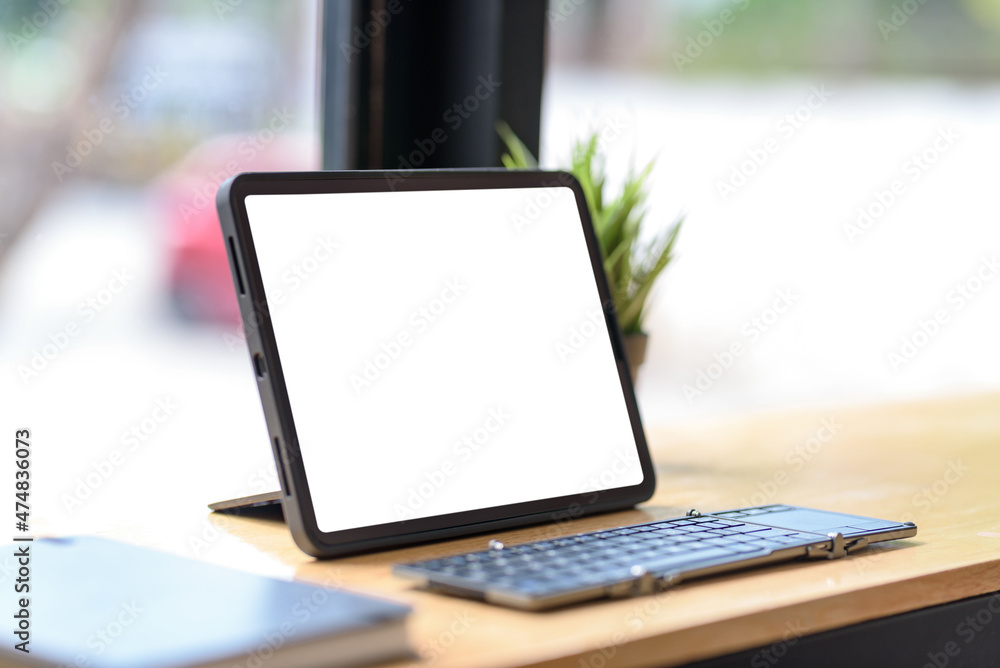 Poster tablet computer blank white screen with keyboard on wooden table. mock up.