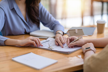 Woman real estate agent talking to client in office. Signing home purchase contract with customer.