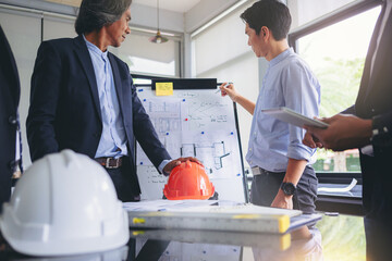 Contractor and engineer with blueprints discuss at a modern construction site, Engineers in...