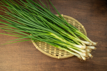 Fresh spring onion in bamboo basket on wooden background.