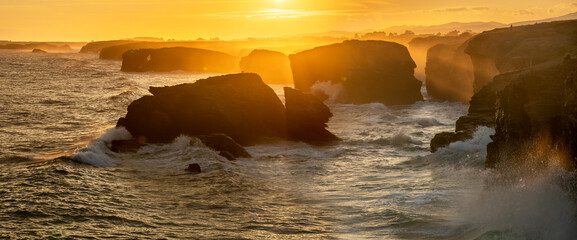 Playa de las Catedrales-huge, ocean waves crashing about rocky cliffs at sunrise