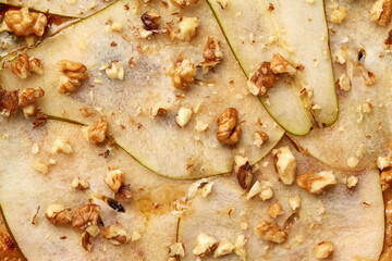Closeup of thin slices of pear and walnuts on pizza with gorgonzola