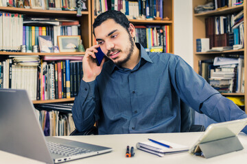 Young entrepreneur talks on his cell phone while working from home